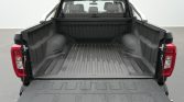 Pickup truck with tailgate down, showing an empty, ribbed cargo bed and rear seating visible through the rear window.