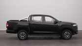Black four-door pickup truck shown in profile with a chrome roll bar over the bed in an indoor setting for showroom use.