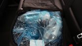 Blue plastic-wrapped package inside a car trunk or back seat area, secured in a bag.