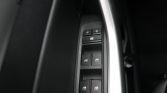 Driver-side car door panel with power window switches and lock controls beside a silver trim, close-up view.