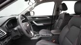 Front cabin of a modern car showing the steering wheel, driver and passenger seats with black upholstery and red stitching, and a center console.