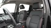 Front interior of a car with black leather seats and red stitching; steering wheel on the left and center console visible.