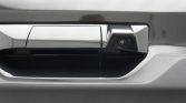 Close-up of a car door handle with a small rearview camera embedded in the handle edge.