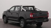 Rear three-quarter view of a dark gray Maxus pickup with a chrome roll bar and bed, indoors.