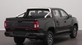 Black Maxus T90 EV pickup truck rear view with chrome sports bar and red taillights in a showroom setting