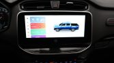 In-car touchscreen displaying a blue pickup truck graphic and colorful app tiles on the dashboard infotainment system.