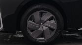 Close-up of a car wheel with a modern geometric alloy rim and low-profile tire, on a dark vehicle body.