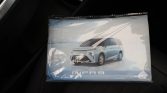 Boxed model car showing a light-blue minivan labeled 'MIFA 9' placed on a car seat.