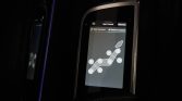 Car seat adjustment display showing a diagram of seat positions and adjustment points on a touchscreen panel in a dark cabin.