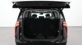 Rear of a black SUV with the tailgate raised, showing the cargo area and upright third-row seats visible behind the front seats.
