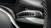 Close-up of a car's automatic gear selector showing P, R, N, D with a small parking assist icon on a glossy panel between the driver and passenger areas.