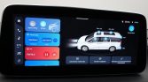 In-car touchscreen showing car settings and multimedia controls with a diagram of a white SUV on the right side of the display panel.