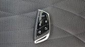 Car key fob with lock/unlock/trunk buttons resting on a perforated car seat surface
