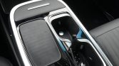 Close-up of a car center console showing a wireless charging pad and a cup holder with chrome trim.