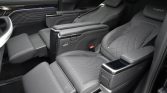 Rear passenger area of a luxury SUV with two captain seats in gray quilted leather and a central console armrest.