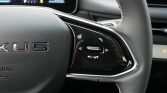 Close-up of a car steering wheel with a glossy right-side control panel: scroll wheel, phone button, and media controls.