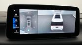 Infotainment screen showing a white SUV in a 360-degree parking view, with top-down and side angles on the display
