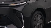 Close-up of the front left section of a dark car, showing a slim LED headlight, angular bumper, and chrome accents near the bumper edge with a visible alloy wheel.