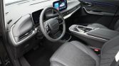 Interior of a modern car showing a digital instrument cluster, center touchscreen, and grey stitched seats with a long center console and ambient lighting.