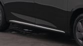 Close-up of a dark gray minivan's lower side with a chrome running board and wheel nearby.