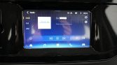 In-car touchscreen displaying DAB radio interface with options DAB, FM, AM and a blue playback bar at the bottom.