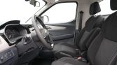 Front interior of a car showing the steering wheel, dashboard, and two black fabric seats with white stitching