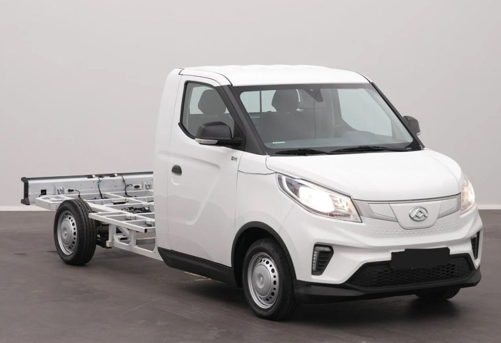 Three-quarter front view of a white cab-forward utility truck with an exposed rear chassis for a cargo bed attachment.