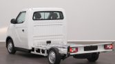 Rear-left view of a white cab-forward pickup with an empty flatbed chassis, no cargo.