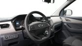 Driver's cockpit inside a modern SUV, steering wheel with logo and dashboard controls visible