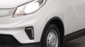 Front-left section of a white van showing the headlight, bumper, and wheel.