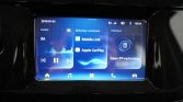Infotainment touchscreen showing music, mobile link options (Mobile Link, Apple CarPlay) and Bluetooth status panel in a car interior.