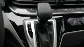 Automatic gear selector in a car with P R N D gears visible and climate controls to the right and center console finishings surrounding it.