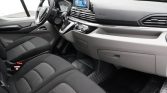 Modern car interior with a touchscreen infotainment display, steering wheel, and black/gray fabric seats viewed from the passenger side
