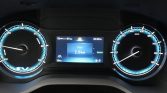 Car dashboard displaying instrument cluster: left and right speedometers with blue accents, center digital screen shows Trip 1 at 1.6 km, EV indicator visible, READY status and time 03:34 pm.
