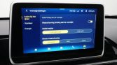 Car infotainment screen showing Dutch driver-assistance settings: front collision alerts, assist mode options, and warning level, on a blue menu screen in the car dashboard.