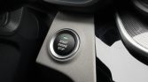 Push-button engine start/stop on a car's center console, with a green indicator light (close-up).
