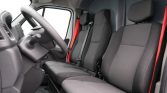 Interior of a vehicle cabin showing driver and front passenger seats with black upholstery and red seat belts.