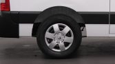 Wheel of a white van with black trim and silver hubcap visible along the side panel edge.