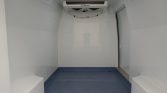 Interior of a white refrigerated cargo area with a ceiling-mounted Thermo King cooling unit and blue non-slip floor area at the back of the van