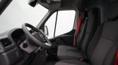 Interior view of a vehicle cabin showing the steering wheel, dashboard, and three front seats with red seatbelt visible on the side seat path to the right of the image.