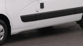 White van side view with long black plastic protective strip along the lower body and door handle visible.