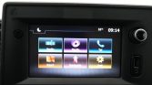 Infotainment touchscreen with six colorful app tiles: Radio, Media, Tel, Kaart (Map), Navigate, Inst (Settings) on a car dashboard.