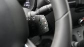 Close-up of a car steering wheel with buttons for media, volume, and phone controls.