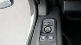 Driver-side door control panel with power window switches and a circular mirror adjustment pad nearby.