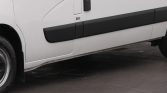 White van side view with black protective molding running along the lower door panel and a wheel visible at left.