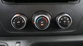 Car climate control panel with three knobs: left for fan speed and airflow, middle for temperature with A/C on blue/red scale, right for defrost and vent modes with recirculation indicator nearby