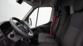 Interior view of a cargo van cabin showing the steering wheel, dashboard, and three front seats with red seat belts.