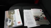 Several car brochures and manuals laid out on a car seat, featuring images of vehicles on the covers.