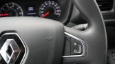 Close-up of a Renault steering wheel showing the logo and a right-side control panel with R and O labels, blurred dashboard in the background