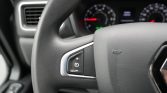 Steering wheel with cruise control buttons on the left; blurred dashboard gauges in the background.